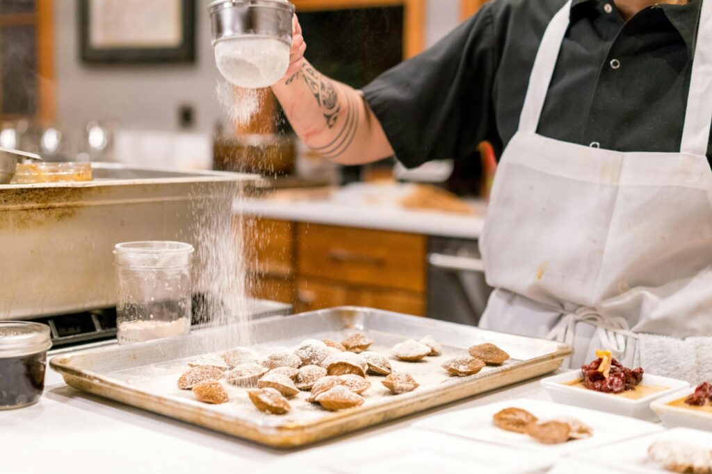 A pastry chef dusting powdered sugar over pastries.